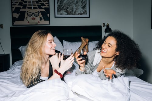 Two women having a good time on a hotel bed