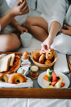 Couple eating room service breakfast on the hotel bed