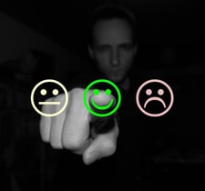 Person using their index finger to choose how satisfied they are with their service using smily face images