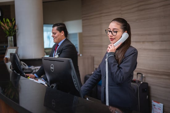 Two hotel receptionists taking calls at the front desk