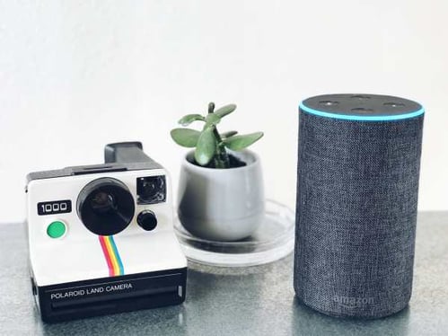 Amazon Alexa next to a retro polaroid camera
