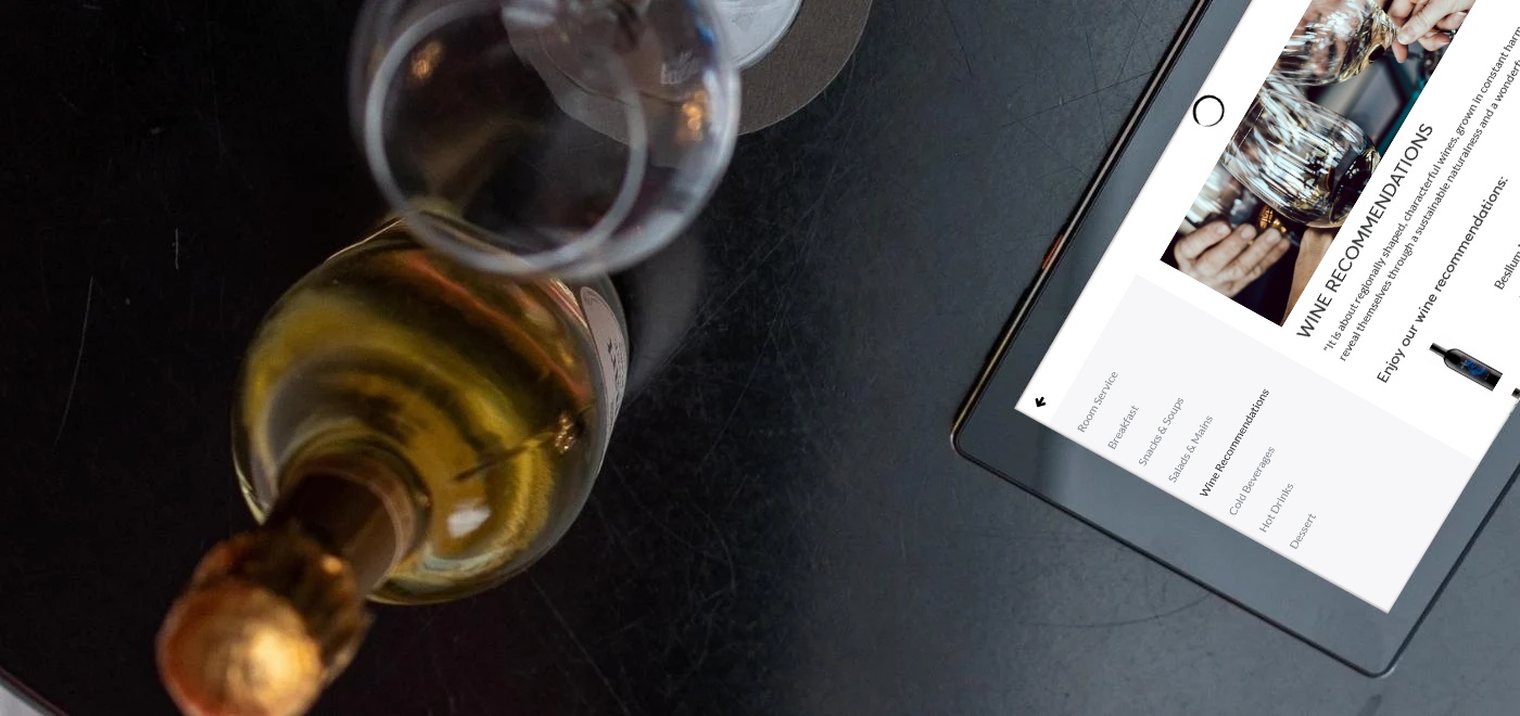 SuitePad tablet on a table with a glass and a bottle