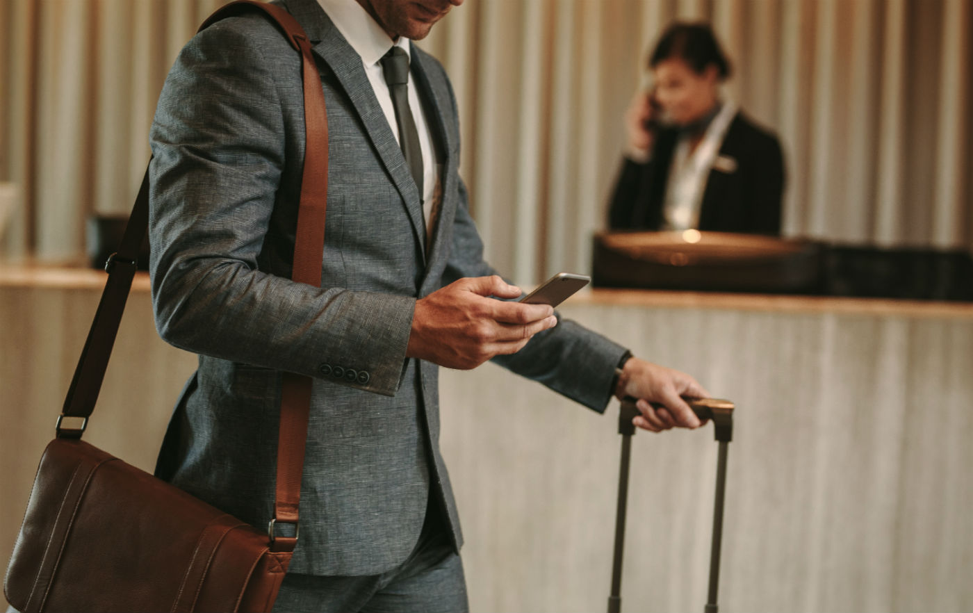 Ein Mann mit einem Koffer nutzt eine App