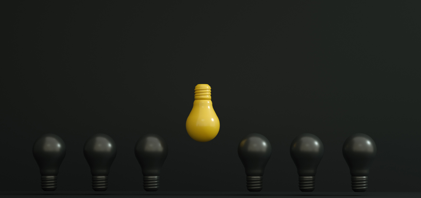 A yellow light bulb above six black light bulbs